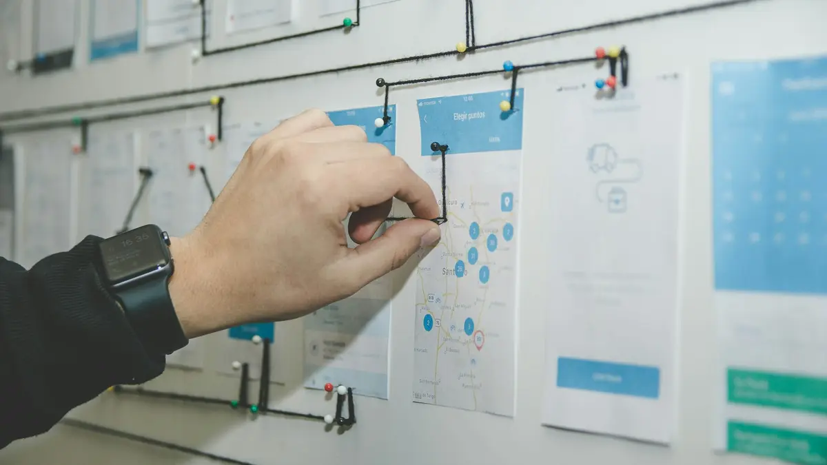 A hand pinning a card to a wall covered in columns of notes