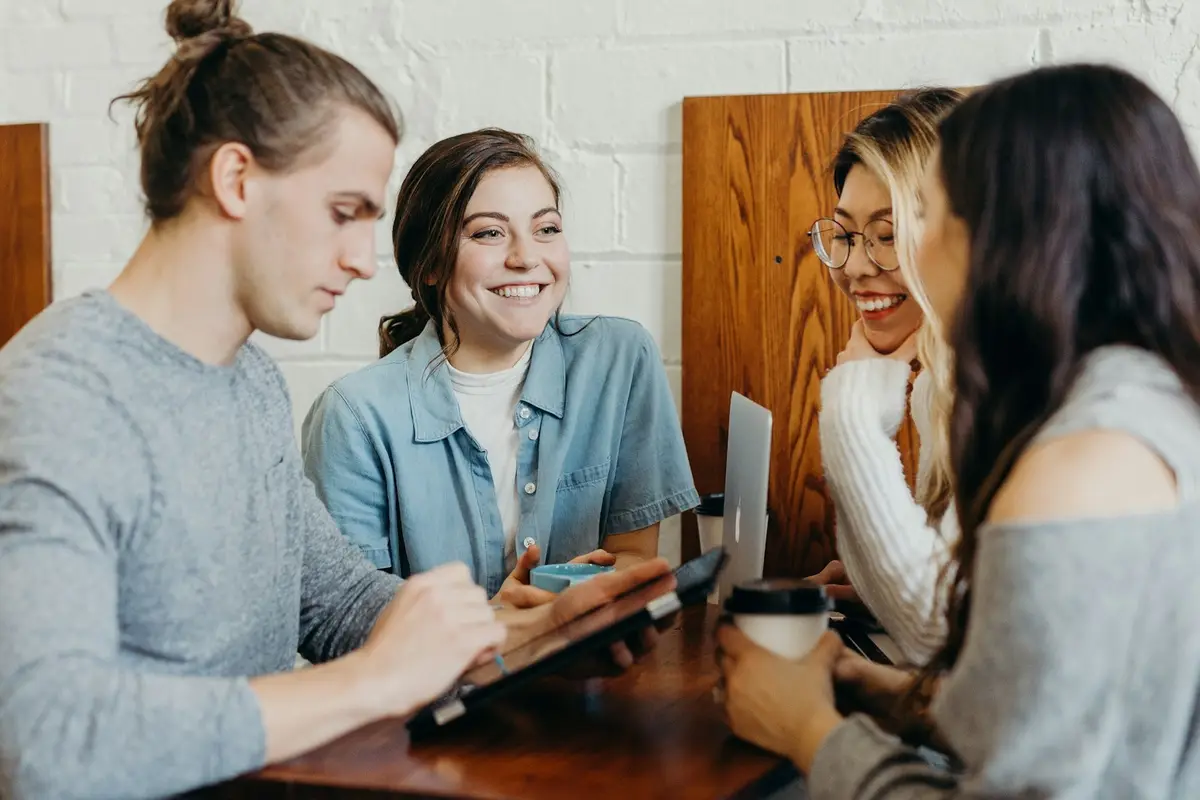 Four colleagues looking at a laptop together and smiling
